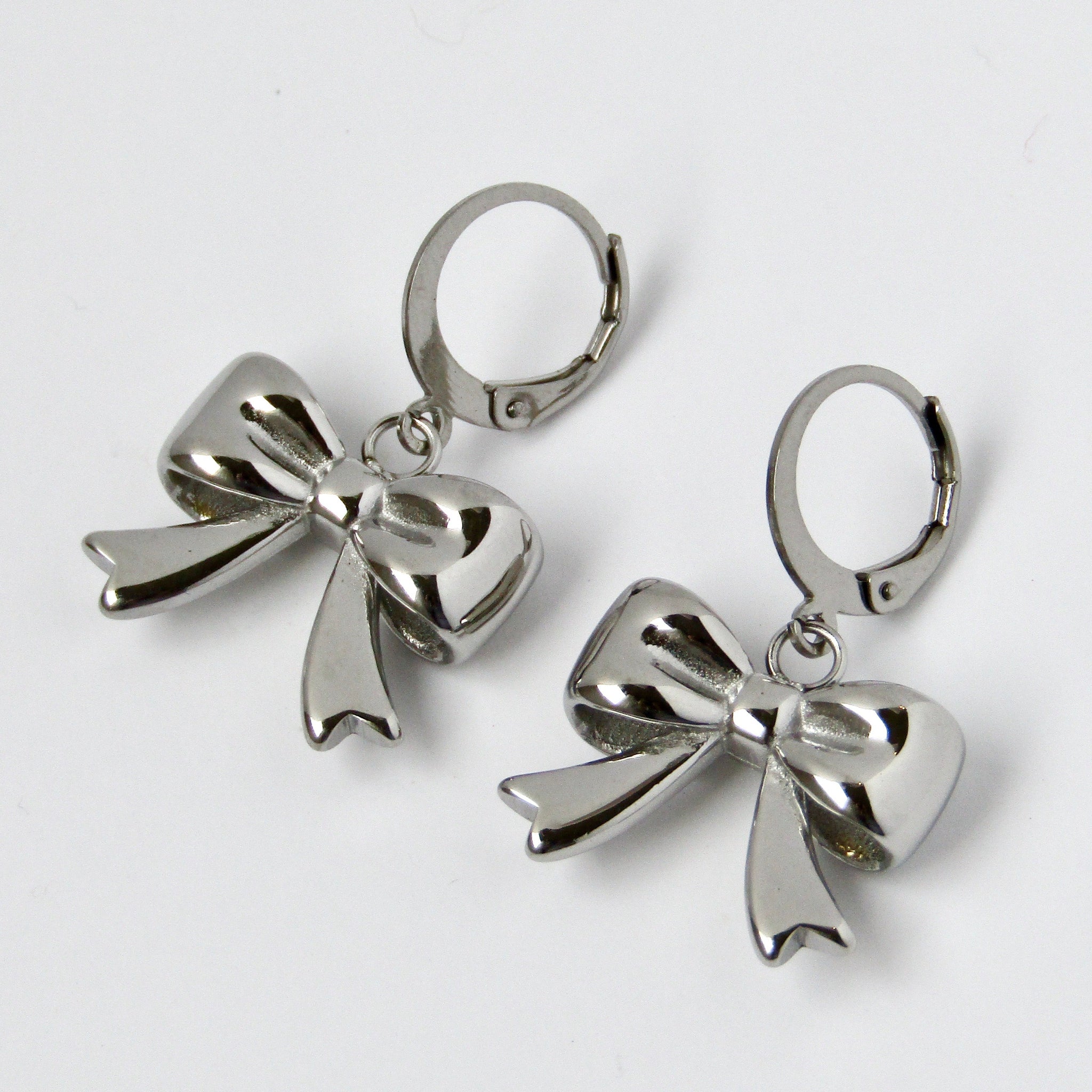 Silver bow-shaped earrings on a light gray background